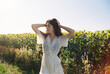 © Polina Kovalova/Stocksy - A brunette woman in a white dress posing amidst a sunflower field