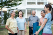 © Pavitra - Group of elderly people holding exercise mat with trainer in the garden.