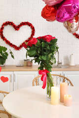 Wall Mural - Bouquet of beautiful roses and burning candles on dining table in festive kitchen. Valentine's Day celebration