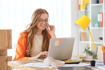 Wall Mural - Female web designer working with laptop at table in office