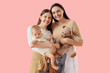 © Pixel-Shot - Young lesbian couple with their little baby and toy bear on pink background