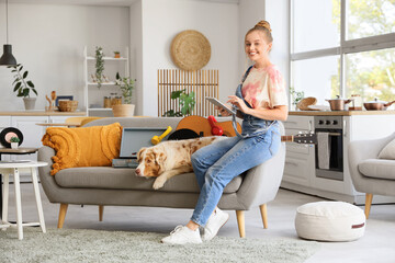 Wall Mural - Young woman using tablet computer with Australian Shepherd dog and record player on sofa at home