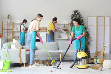 Canvas Print - Team of young janitors cleaning in room after New Year party