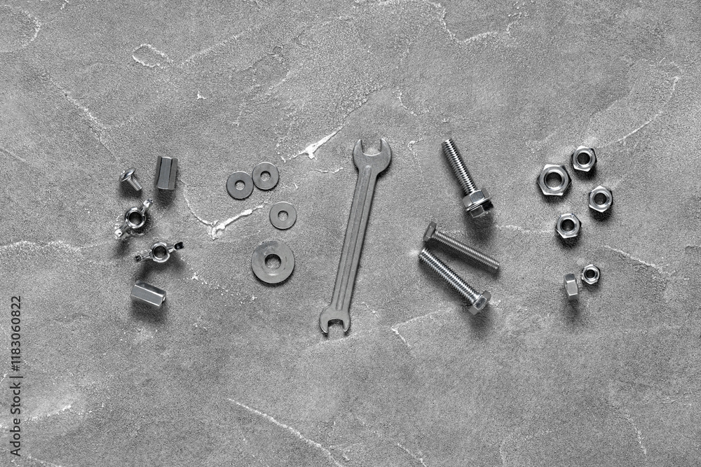 Tap bolts, chrome nuts and wrench on grey grunge background