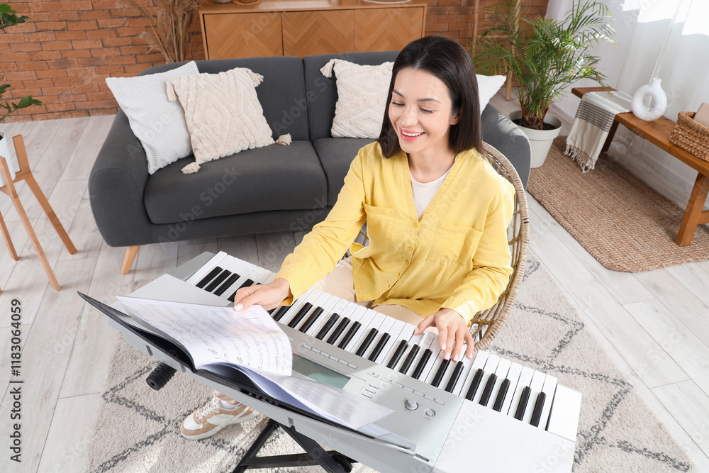 Happy young woman playing synthesizer at home