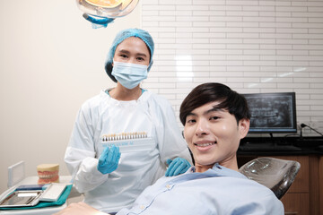 Wall Mural - Portrait of Asian female dentist and male patient with tooth whitening shades implant, happy smile, and looking at camera in dental clinic, mouth hygiene healthcare work in a doctor's hospital.