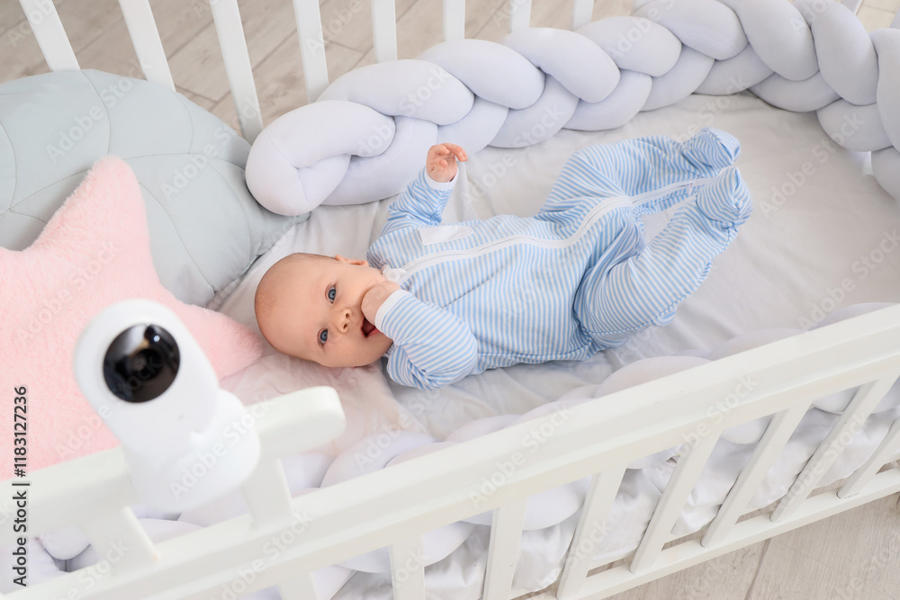 Cute little baby lying in crib with camera at home