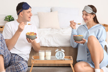 Wall Mural - Young couple with cereal rings having breakfast in bedroom