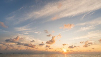 Wall Mural - sunset sky clouds over sea in the evening with orange, yellow sunlight on golden hour, horizon sea s