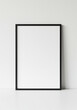 © Dostain - Black frame leaning against white wall, perfect for interior design inspiration