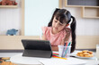 © suriya - Little girl doing homework with modern tablet at home