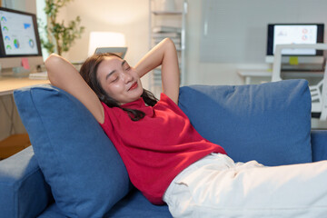 Sticker - Young asian businesswoman relaxing on the sofa with hands behind her head, eyes closed, enjoying a moment of peace and quiet after a productive day working from home