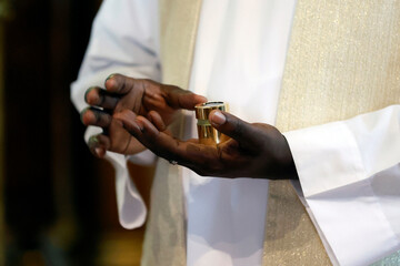 Wall Mural -  Catholic baptism ceremony. African priest with Holy Chrism in hands.