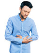 © Krakenimages.com - Hispanic man with beard wearing casual business shirt with hand on stomach because indigestion, painful illness feeling unwell. ache concept.