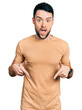 © Krakenimages.com - Hispanic man with beard wearing casual t shirt pointing down with fingers showing advertisement, surprised face and open mouth