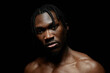 © Seventyfour - Portrait of shirtless fit Black man with braids hairstyle staring at camera while confidently posing in in hard light against black backdrop, copy space