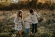 © Cavan Images - Cute interaction between three sweet siblings outdoors, grassy field