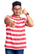 © Krakenimages.com - Handsome latin american young man wearing casual clothes and glasses smiling doing talking on the telephone gesture and pointing to you. call me.