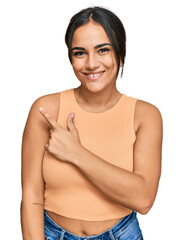 Wall Mural - Young brunette woman wearing casual clothes cheerful with a smile of face pointing with hand and finger up to the side with happy and natural expression on face