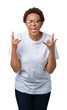 © Krakenimages.com - Beautiful young african american woman wearing glasses over isolated background shouting with crazy expression doing rock symbol with hands up. Music star. Heavy concept.