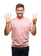 © Krakenimages.com - Young handsome man over isolated background showing and pointing up with fingers number seven while smiling confident and happy.