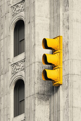 Wall Mural - Urban Contrast: Vibrant Yellow Traffic Light Against Historic Stone Building