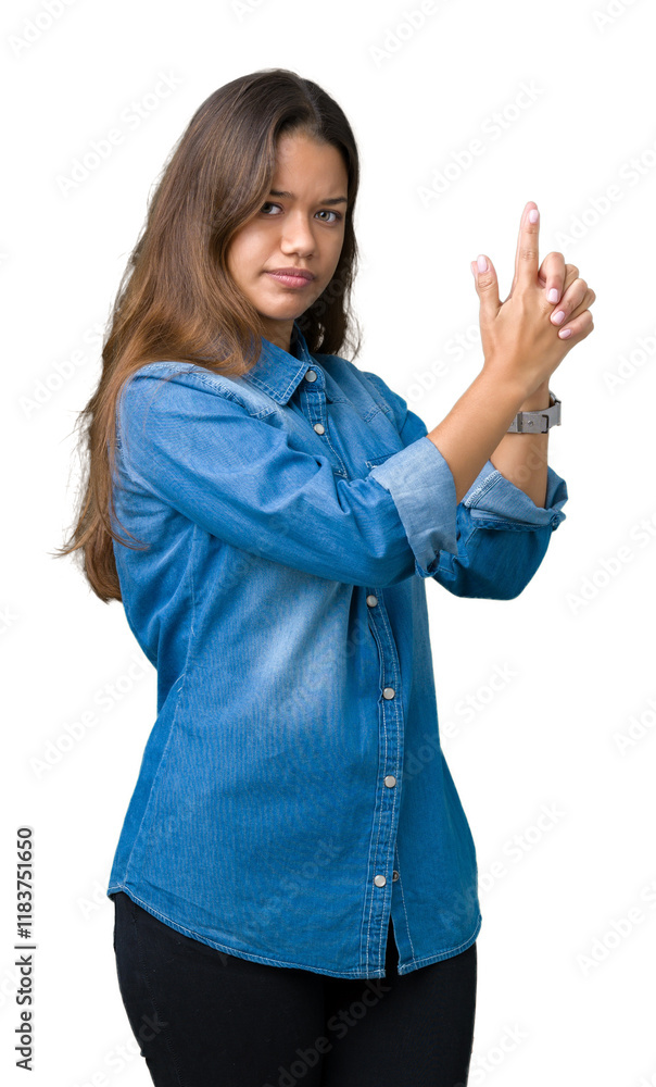 Young beautiful brunette woman wearing blue denim shirt over isolated background Holding symbolic gun with hand gesture, playing killing shooting weapons, angry face