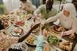 © AnnaStills - High angle shot of biracial family clinking glasses with champagne while enjoying family dinner