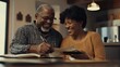 © Johannes - Mature smiling couple sitting and managing expenses at home. Happy mid black man and woman paying bills and managing budget. Middle aged african american couple checking accountancy and bills.