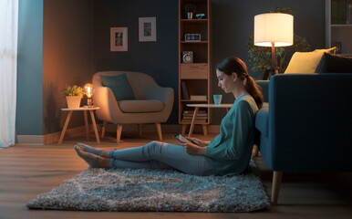 Wall Mural - Young woman sitting on the floor and connecting with her tablet