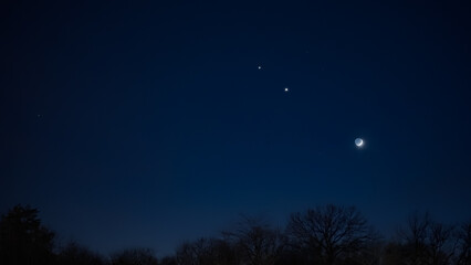 Wall Mural - crescent young moon with stars, planets and countryside silhouettes.