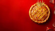 © Daniel - galette des rois bien dorée avec une couronne - posée sur un fond rouge avec espace vide - vue de dessus