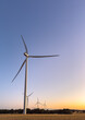 © Austockphoto - four towering white wind turbines on farming land at dusk