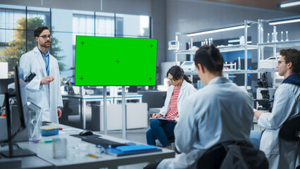 Leinwandbilder - Group of Students Listening to Their Biology Professor Who Uses TV Monitor with Green Screen Template in a Laboratory. Team of Bioengineers Having a Meeting and Discussing Gene Editing Ideas