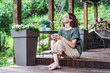 © olezzo - Young happy smiling Caucasian woman sitting on the wooden terrace of a country house enjoying the summer weather