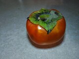 Orange delicious persimmon on a gray background. Seasonal fruit on a gray background.