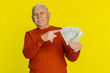 © Andrii Iemelianenko - Rich happy senior old man pointing on money dollar cash banknotes bills fan, success business career, lottery winner, big income wealth pension. Elderly grandfather pensioner on yellow background