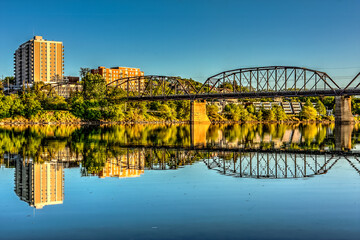 Canvas Print - A bridge spans a river with a city in the background