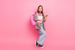 © deagreez - Charming young schoolgirl posing with a pink backpack and notebook against a pink background, flashing a peace sign