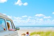 A family of four driving happily near the waves, their dog upfront