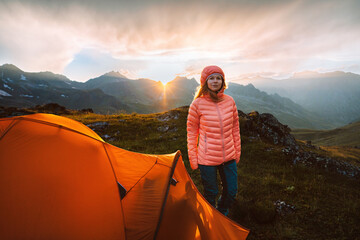 Wall Mural - Woman trekking with tent camping gear in mountains hiking travel adventure outdoor, healthy lifestyle summer active vacations trip - girl in warm down jacket enjoying sunset landscape