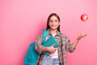 © deagreez - Smiling young girl in casual checkered shirt holding books with a red apple above her hand on a pink background
