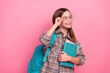 © deagreez - Smiling girl in glasses holding a book and backpack standing against a pink background