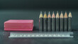 © Gomez - A row of sharpened pencils lined up neatly next to a bright pink eraser and a ruler