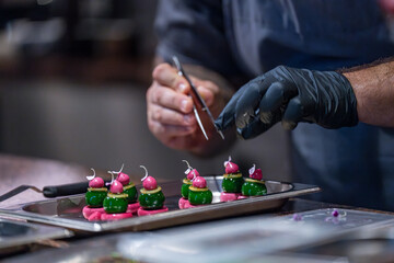 Gros plan sur la fin de préparation d'une bouchée par un chef étoilé en cuisine.