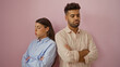 © Krakenimages.com - Couple standing back to back with arms crossed looking unhappy over a pink background conveying relationship conflict.