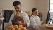 © Krakenimages.com - Man and woman bakers working together in a bakery, with the man holding a tablet and the woman using a computer, surrounded by fresh baked goods