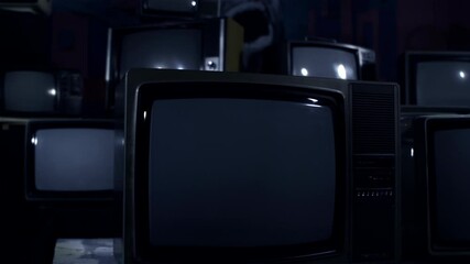 Wall Mural - vintage tv with green screen surrounded by stacked tvs in dark room - dolly shot - 100% real video, 