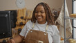 © Krakenimages.com - Woman smiling in a bakery with shelves of bread in the background, wearing a white t-shirt and brown apron, in an indoor setting