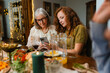 © DZ FILM/Stocksy - A woman is sitting at a festive table with her mother